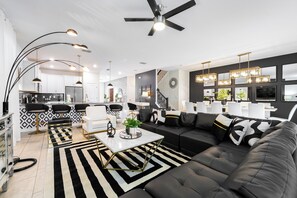 A modern living room with a black and white striped rug, a black sofa, and a white coffee table. - Your Own Magic Kingdom 9 Bedroom Villa (Kissimmee)