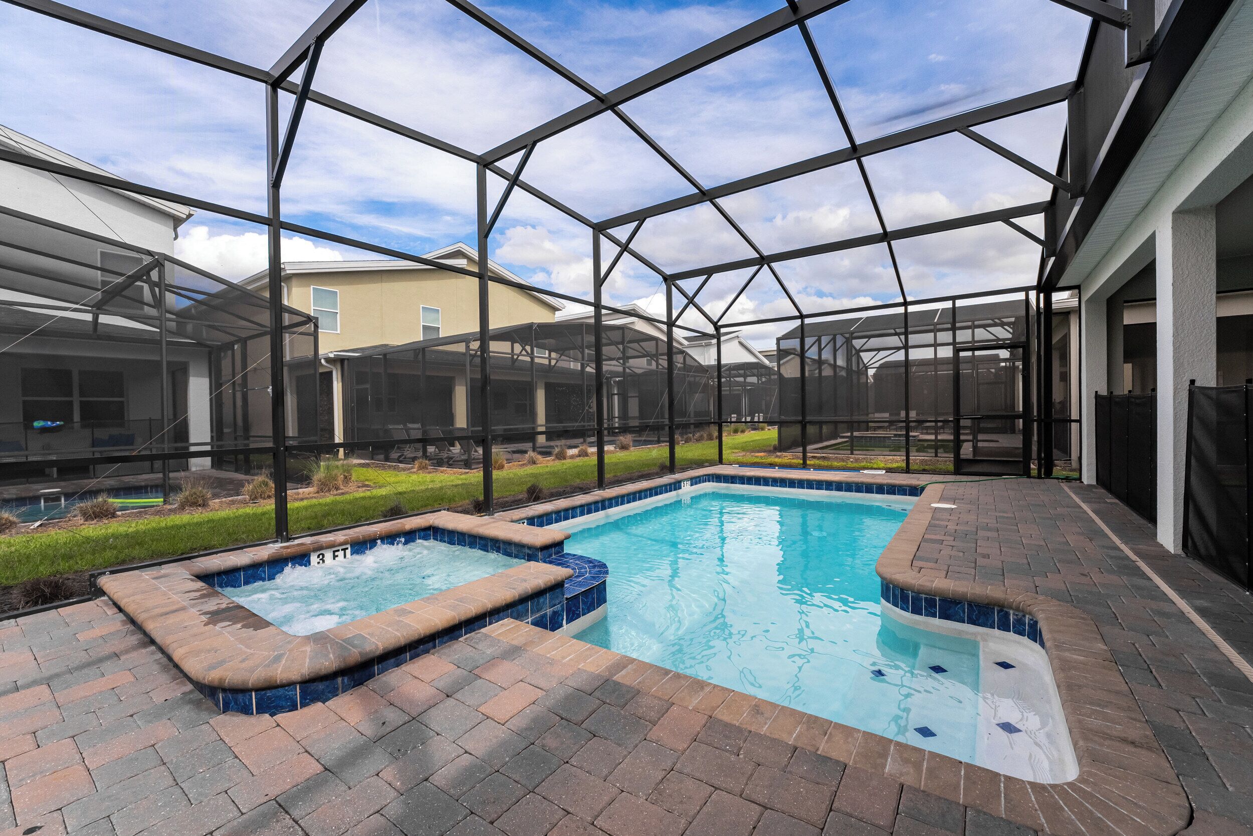 A swimming pool with a hot tub, surrounded by a covered patio area with brick flooring and a metal roof structure.