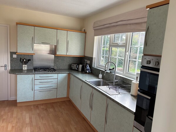 A compact kitchen with a gas stove, toaster, sink, and oven.