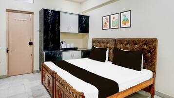 A bedroom with a wooden bed, a wardrobe, a small kitchenette, and a door.