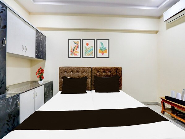Une chambre à coucher comprenant un lit, deux oreillers, une table de chevet, une commode et trois œuvres d’art encadrées accrochées au mur.