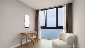 A modern room with a large window, a wooden desk, and a comfortable chair. - Next White Aparthotel Official (Batumi)