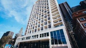 A high-rise hotel with multiple floors, large windows, and a modern architectural design. - Next White Aparthotel Official (Batumi)