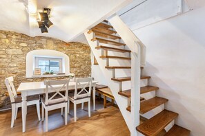 Ein Essbereich mit Steinwand, einer Holztreppe und einem weißen Tisch mit Stühlen.