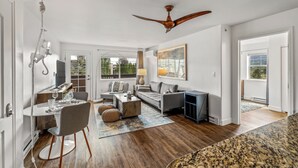 A spacious living area with a dining table, sofa, and a ceiling fan. - Bright, Beautiful First Tracks Condo W/ Pool & Spa 1084 (Steamboat Springs)