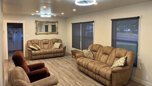 A spacious living room with two brown sofas, a brown armchair, and a large mirror on the wall.