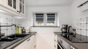 A kitchen with white cabinets, a black countertop, a window with blinds, and a coffee maker. - Apartment 'Ilmhaus 2' with Wi-Fi (Gaden bei Pförring)