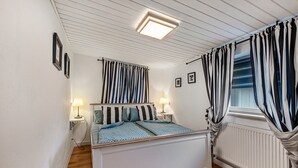A bedroom with a bed, two bedside lamps, a window with curtains, a radiator, and a ceiling light fixture. - Apartment 'Ilmhaus 2' with Wi-Fi (Gaden bei Pförring)