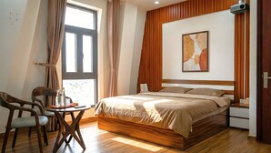 A bedroom with a wooden bed, a dining table with chairs, a projector, and a large window with curtains. - Katka Riverside Homestay Hai Phong (Hai Phong)