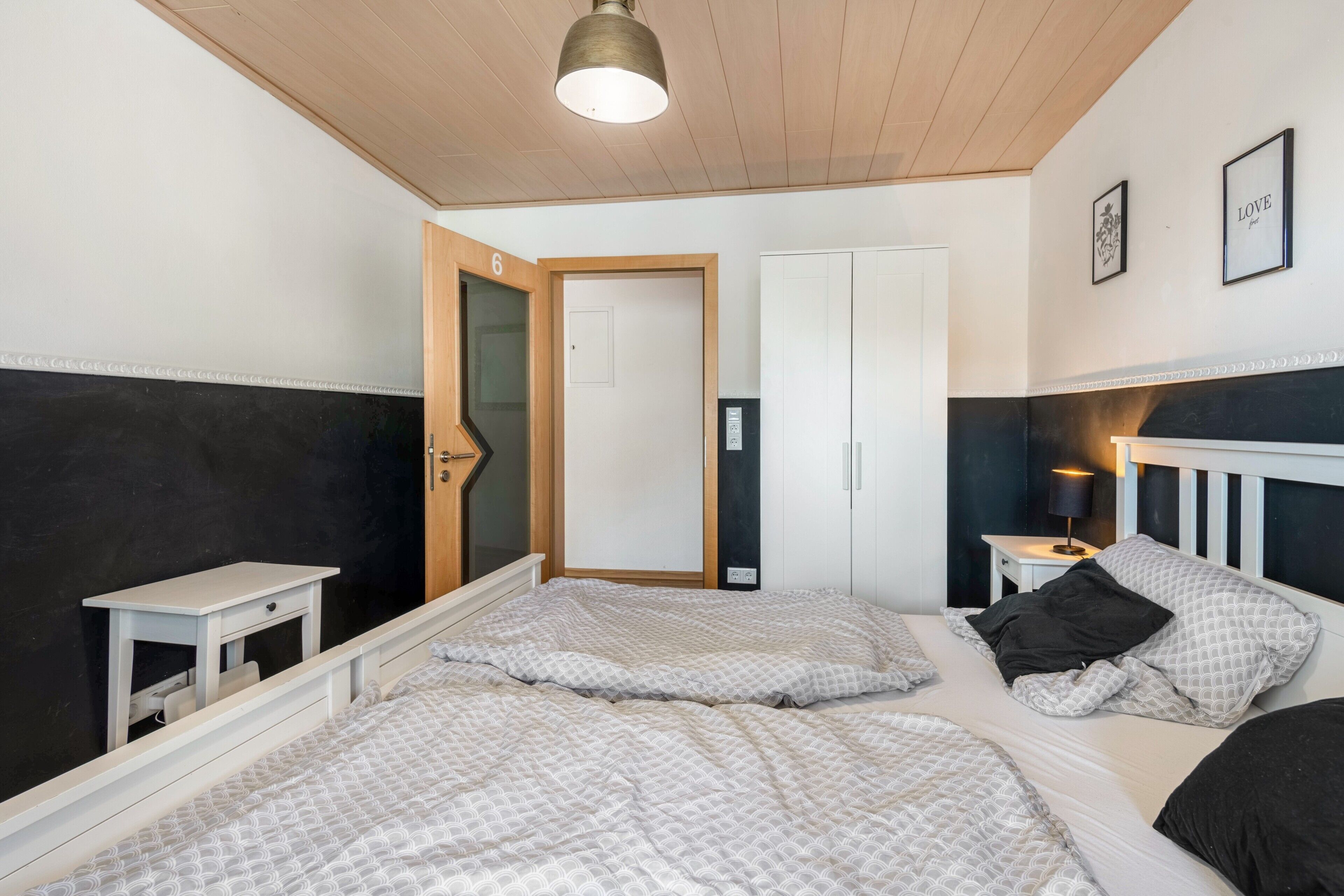 Un dormitorio con dos camas, una mesita de noche, una puerta y una lámpara en el techo.