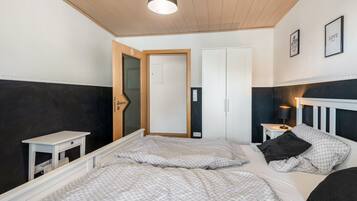 Un dormitorio con dos camas, una mesita de noche, una puerta y una lámpara en el techo.