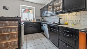 A modern kitchen with dark cabinetry, a dishwasher, and a tiled backsplash. - Holiday Home 'Am Limes' with Private Terrace, Private Garden and Wi-Fi (Altmannstein)