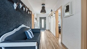 A hallway with a dark textured wall, a white-framed bed with striped pillows, a hanging lamp, and a door at the end. - Holiday Home 'Am Limes' with Private Terrace, Private Garden and Wi-Fi (Altmannstein)