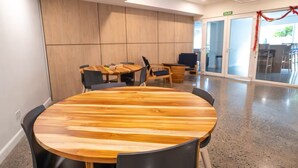 A conference room with a round wooden table, black chairs, and a wooden panel wall. - Pacific Point 1106B (Jaco)