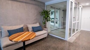 A modern living room with a sofa, a round wooden coffee table, and a potted plant. - Pacific Point 1106B (Jaco)