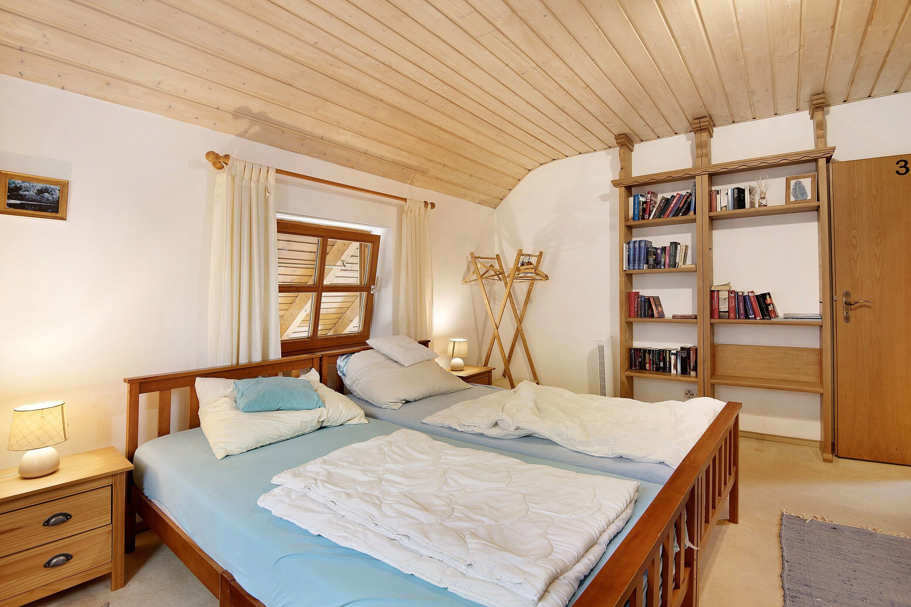 A bedroom with a wooden bed, bedside tables, a wardrobe, and a bookshelf.