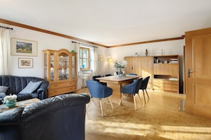 Un salon comprenant un canapé, des fauteuils, une table à manger et un buffet en bois.