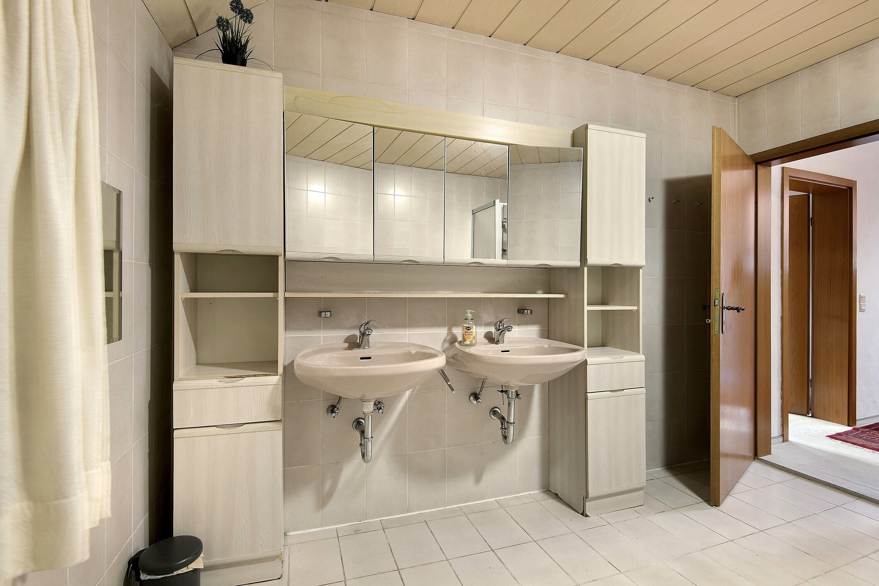 Een badkamer met twee wastafels, een spiegel en een kast.