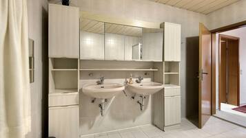 Een badkamer met twee wastafels, een spiegel en een kast.