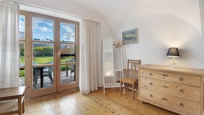 A room with a wooden dresser, a chair, a table, and a view through a glass door to an outdoor area. - Holiday Home 'Landhaus in Pförring' with Balcony and Wi-Fi (Pförring)