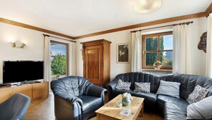 A living room with a large flat-screen TV, leather sofas, a wooden coffee table, and a cabinet. - Holiday Home 'Landhaus in Pförring' with Balcony and Wi-Fi (Pförring)