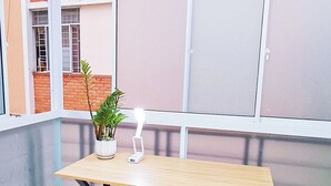 A corner balcony with a wooden table, a yellow chair, a potted plant, and a white lamp. - FSHOME (Ho Chi Minh City)