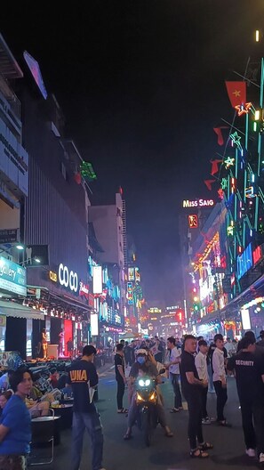 A busy street at night with neon signs and a crowd of people. - FSHOME (Ho Chi Minh City)