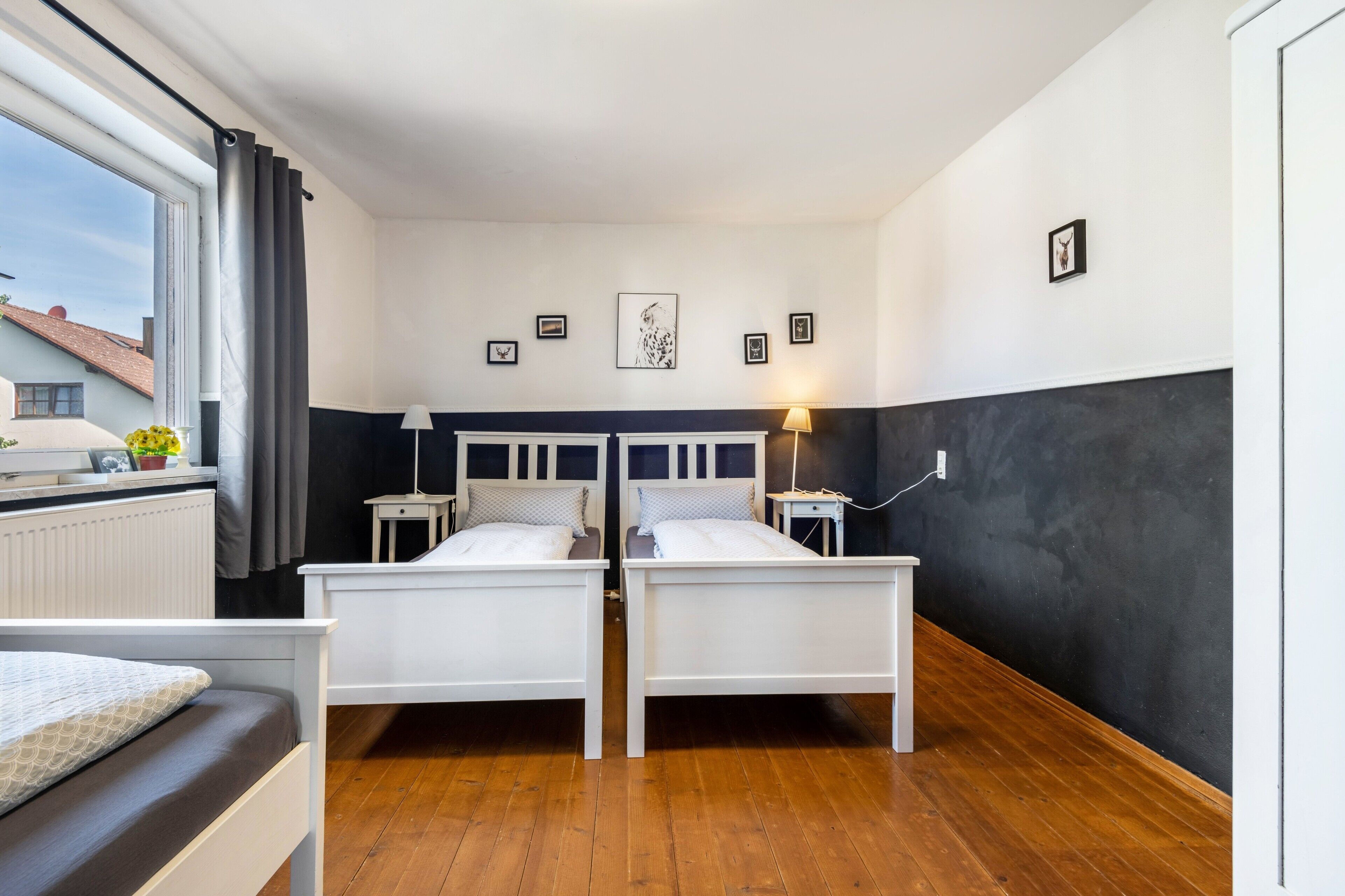 Habitación doble con dos camas, una ventana con cortinas, un radiador y lámparas fijadas a la pared.