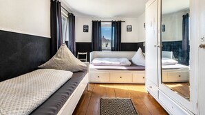 A bedroom with two beds, a wardrobe, a window with curtains, and a view of the outside. - Holiday Home 'Am Sallingbach' with Balcony and Wi-Fi (Sallingberg)