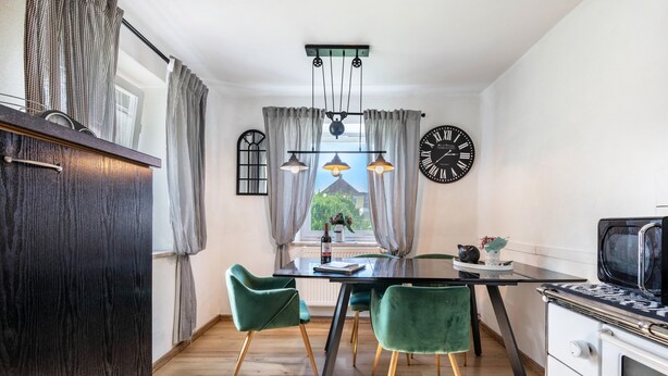 A modern kitchen with a dining table, chairs, a clock, and a window with curtains. - Holiday Home 'Am Sallingbach' with Balcony and Wi-Fi (Sallingberg)