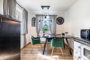 Een moderne keuken met een eettafel, stoelen, een klok en een raam met gordijnen.