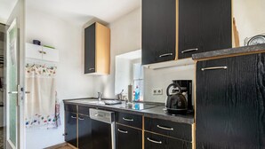 A modern kitchen with black cabinets, a dishwasher, and a kettle. - Holiday Home 'Am Sallingbach' with Balcony and Wi-Fi (Sallingberg)