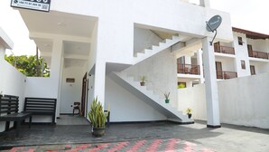 Una villa con una scala che conduce a un balcone, una panca e piante in vaso.