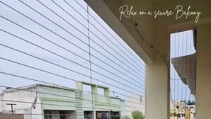 Un balcon doté d’une rambarde en métal, donnant sur un quartier résidentiel avec des immeubles et de la verdure.