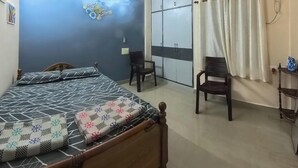 Ein Schlafzimmer mit einem Bett, einem Deckenventilator, einem Kleiderschrank und einem fenster mit Vorhängen.
