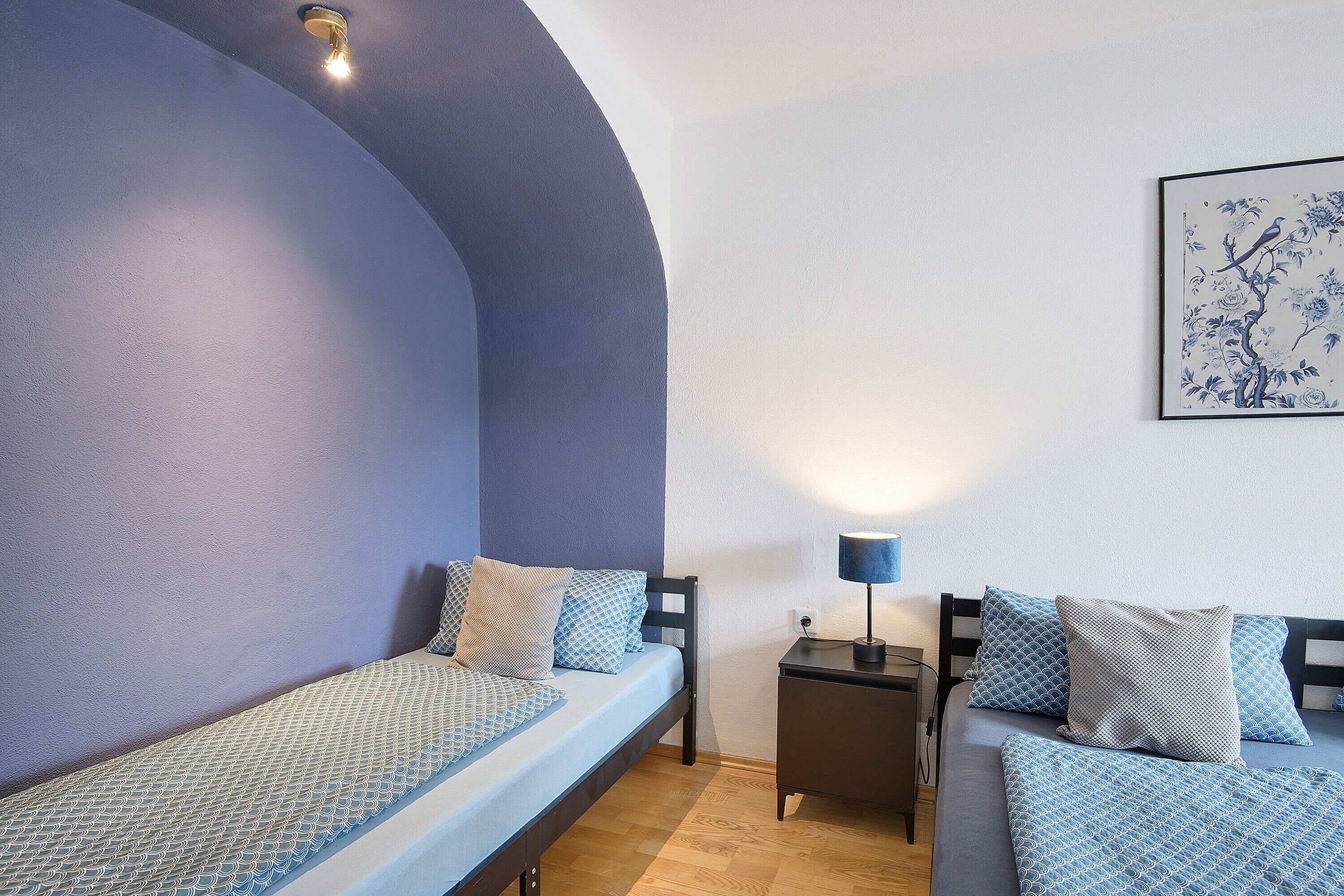 A room with a bed, a nightstand, a lamp, and a wall-mounted artwork.