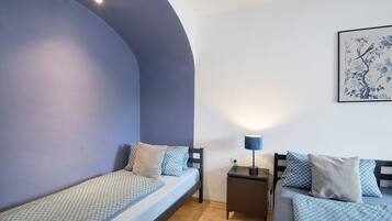 A room with a bed, a nightstand, a lamp, and a wall-mounted artwork.