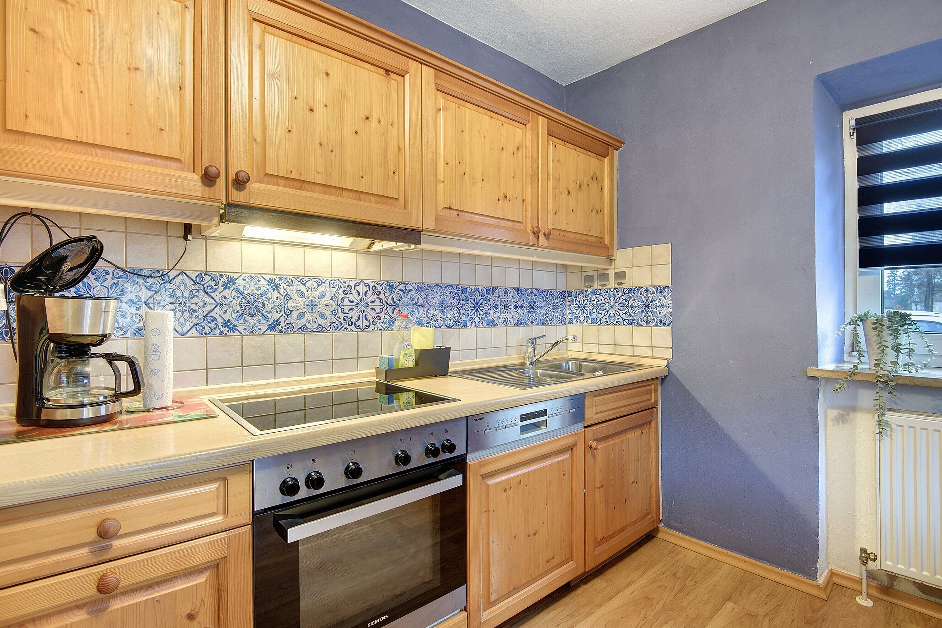 A kitchen with wooden cabinets, a tiled backsplash, a stove, and a dishwasher.