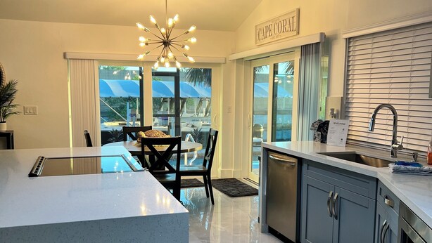 Una cocina moderna con una isla grande, un comedor con candelabro y vistas al exterior.