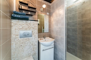 Un baño con pared de azulejos, un lavamanos, un espejo y un perchero para toallas.