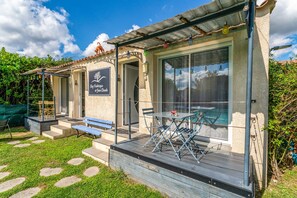 Un patio con mobiliario exterior, una zona de estar cubierta y un cartel con texto.