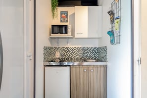 Una cocina compacta con microondas, horno pequeño, lavabo y un armario.