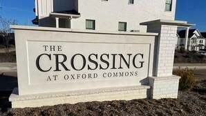 A sign for "The Crossing at Oxford Commons" with a white background and black lettering. - Family-Friendly 3BR Condo Sleeps 9, Ensuite Bathrooms (Oxford)