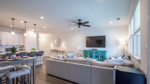 A modern living room with a sofa, a coffee table, and a TV mounted on the wall. - Family-Friendly 3BR Condo Sleeps 9, Ensuite Bathrooms (Oxford)