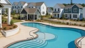 A swimming pool with a wavy design, surrounded by houses with a uniform architectural style. - Family-Friendly 3BR Condo Sleeps 9, Ensuite Bathrooms (Oxford)