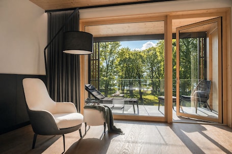 A modern room with a large sliding glass door, a black floor lamp, and two chairs.. Buff Medical Resort