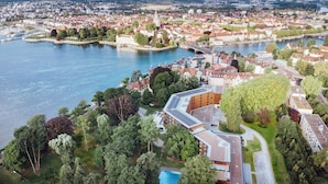 An aerial view of a riverside area with a mix of residential and commercial buildings, a bridge, and a large building with a modern design.