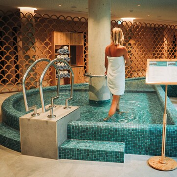 A spa area with a pool, a wooden wall with a lattice design, and a signboard.