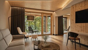 A modern living room with a sofa, chairs, a coffee table, and a TV mounted on a wooden wall.