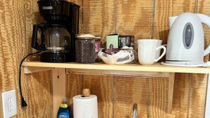 Uma cozinha compacta com cafeteira, chaleira e comodidades básicas.